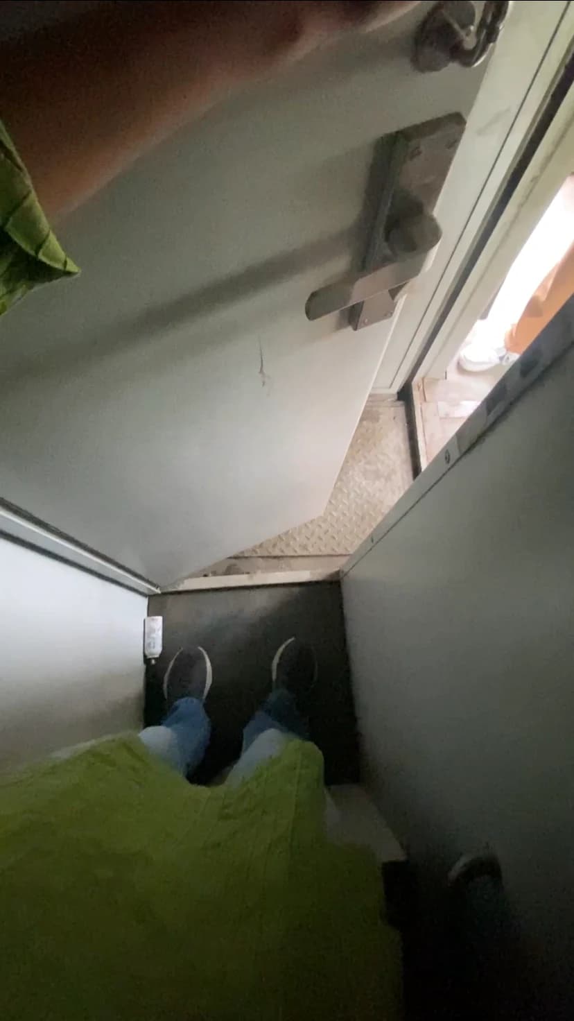 Looking down at feet on the lavatory's threshold, the driving compartment visible through the open door